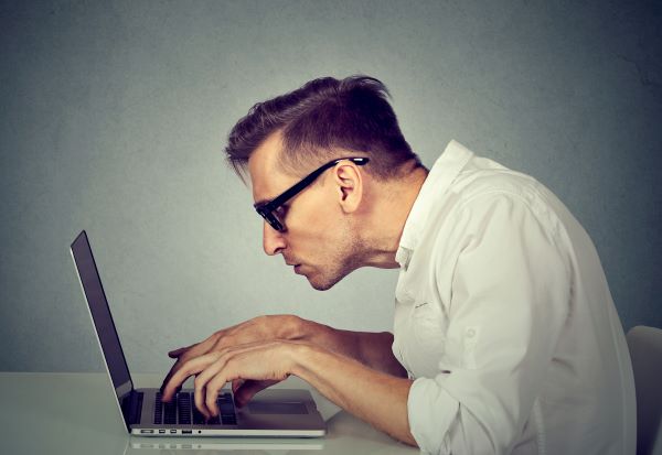 man hunched over his laptop showing poor posture.